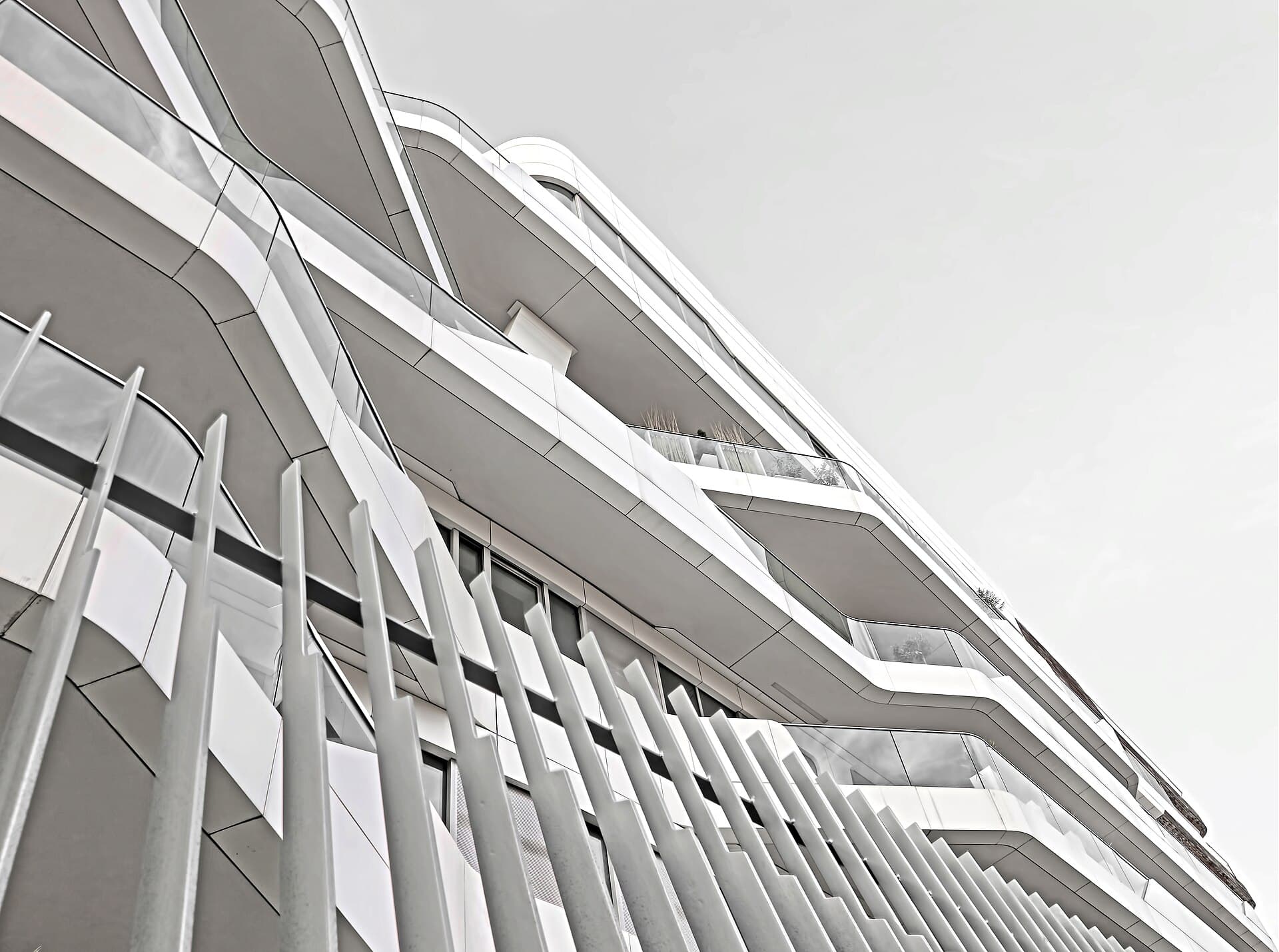 Flowing white balconies on a modern building, seen from below.